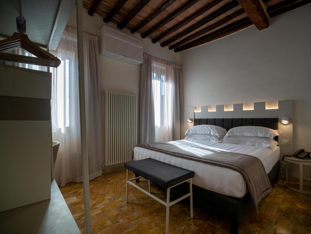 a bedroom with a large bed and a stool at Torre del Fuggisole in Siena
