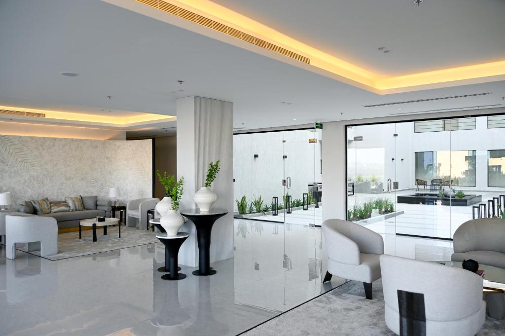 ein Wohnzimmer mit weißen Möbeln und Glaswänden in der Unterkunft بوابة النخيل للشقق الفندقية in Riad