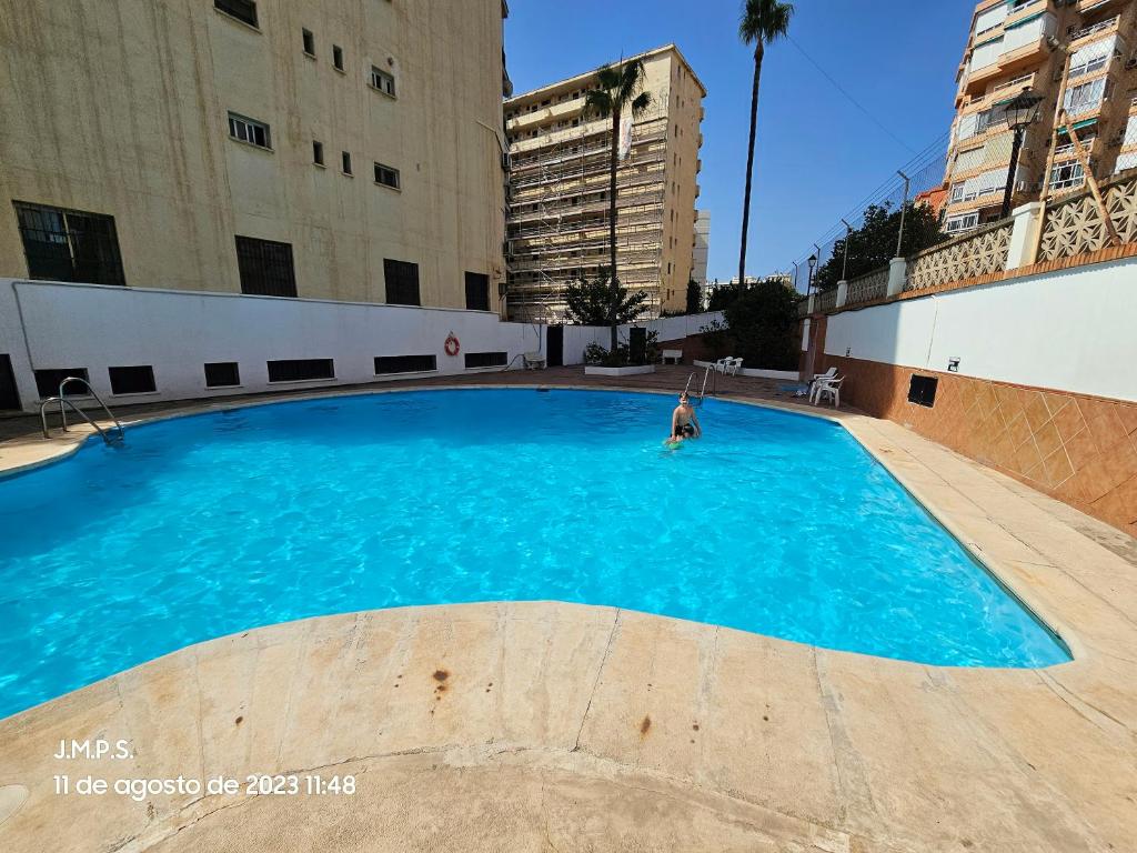 una persona está de pie en una gran piscina azul en Estudio acogedor y tranquilo en zona estupenda, en Fuengirola