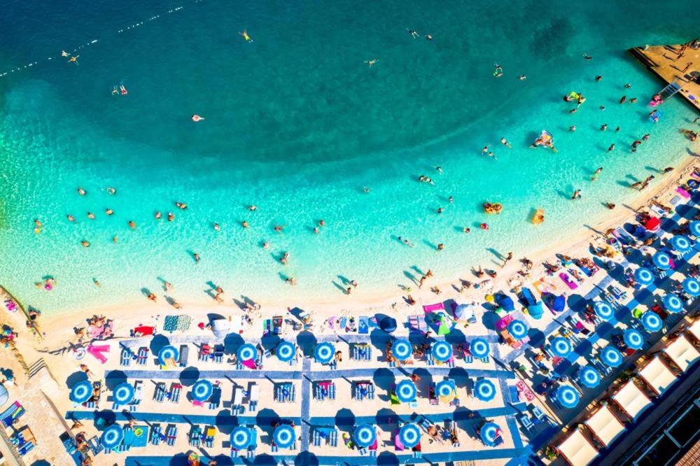 an overhead view of a beach with people and umbrellas at SEA HOUSE pine shade, pool & jacuzzi - PRIVILEGE POINT camping villas in Selce