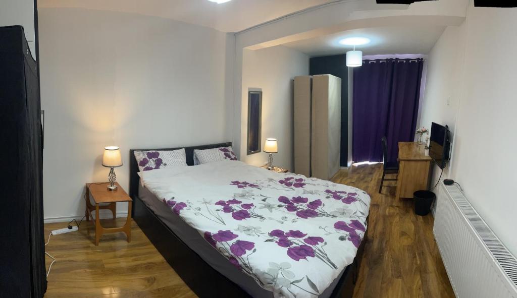a bedroom with a bed with a purple and white blanket at London Heathrow Homes in New Bedfont