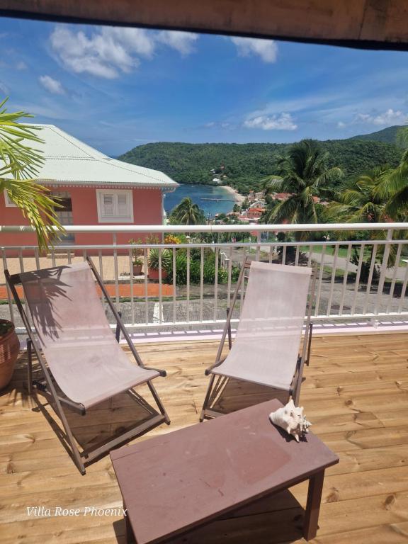 2 sillas y una mesa en el balcón en Rose Phœnix rez-de-jardin piscine et vue mer en Les Anses-dʼArlets