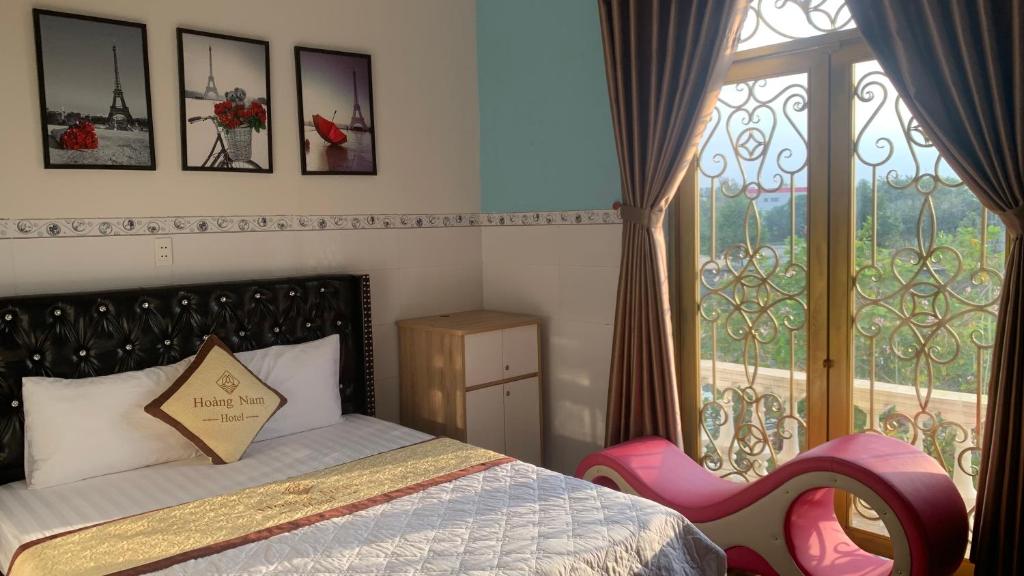a bedroom with a bed and a window with a chair at Hoàng Nam Hotel Bình Dương in Tân Uyên