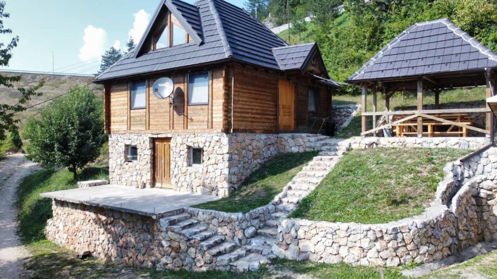 drewniany domek z kamienną ścianą wokół niego w obiekcie Wooden house Nada (Drvena kuća Nada) w mieście Zaovine