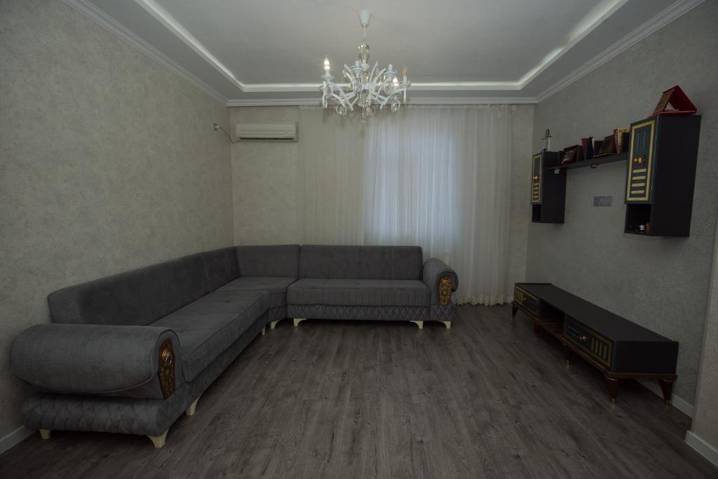 a living room with a couch and a chandelier at Welcome Inn in Baku