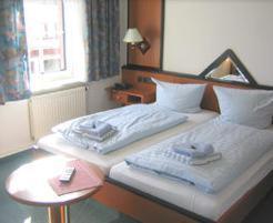 ツヴィッカウにあるHotel Haus Marienthalのベッドとテーブルが備わるホテルルームです。