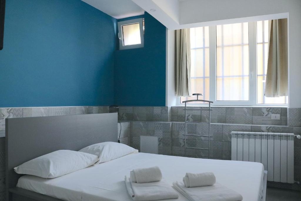 Gambara GuestS House في ميلانو: غرفة نوم بسرير ابيض وجدار ازرق