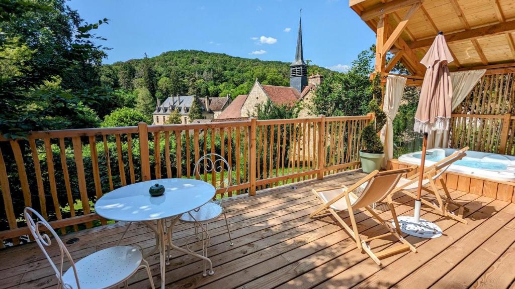 une terrasse en bois avec une table et des chaises ainsi qu'une église dans l'établissement La Cabane du Domaine des Ecus d'Or, à La Bussière-sur-Ouche