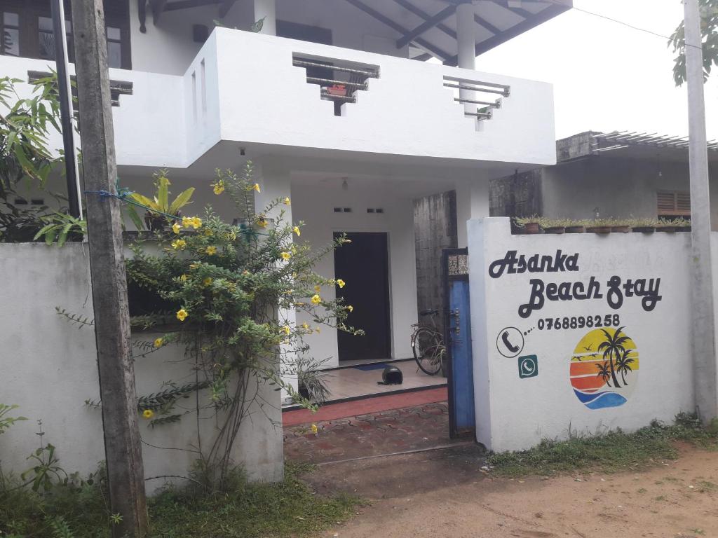 um edifício branco com um sinal em frente em Asanka Beach Stay em Mirissa