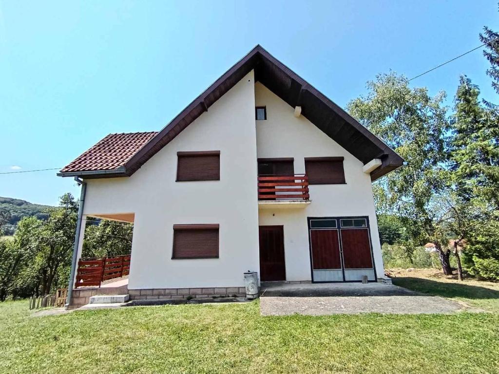 a white house with brown doors on a grass field at Yanks Idila in Zlatibor