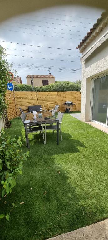 une terrasse avec une table et des chaises sur une pelouse dans l'établissement aux creissauds, à Aubagne