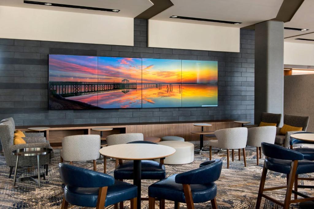 a lobby with tables and chairs and a large screen tv at Courtyard by Marriott Philadelphia South at The Navy Yard in Philadelphia