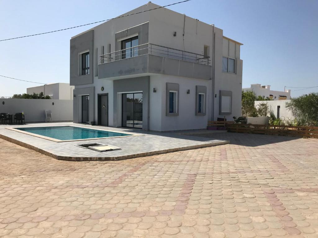 dom z basenem przed nim w obiekcie Villa privé 4 chambres 4 lit double à Djerba en face de la ferme de lotos w mieście Midun