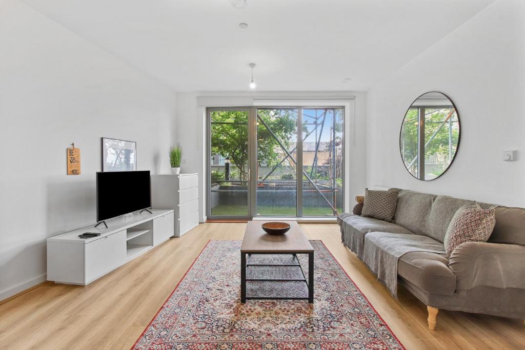 ein Wohnzimmer mit einem Sofa und einem TV in der Unterkunft Centrally Located Modern 2Bed 2Bath Apartment in London