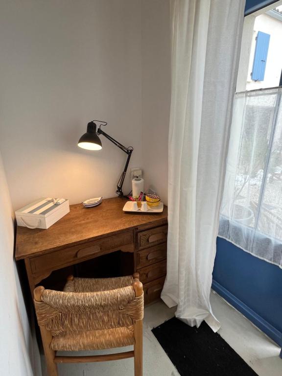 a desk with a lamp and a chair next to a window at LE CLOS DE FLO 17 in Saint-Rogatien