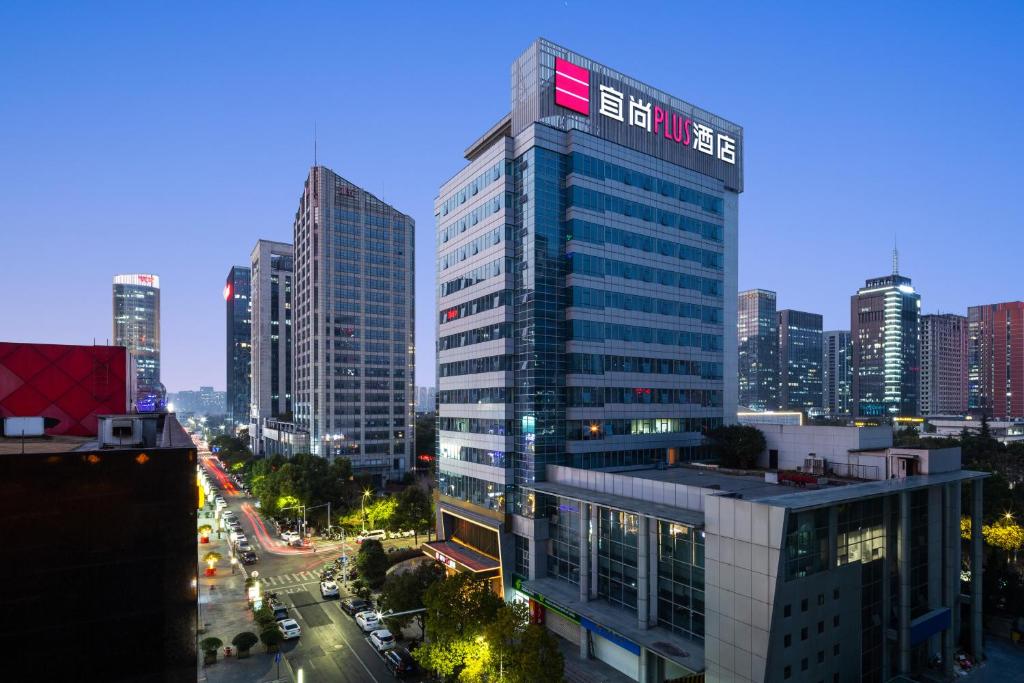 a tall building with a sign on it in a city at ECHARM Plus Hotel - Hangzhou Binjiang Starlight Avenue in Hangzhou