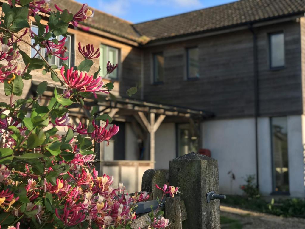 a house with pink flowers in front of a fence at Withy Farm in Canterbury