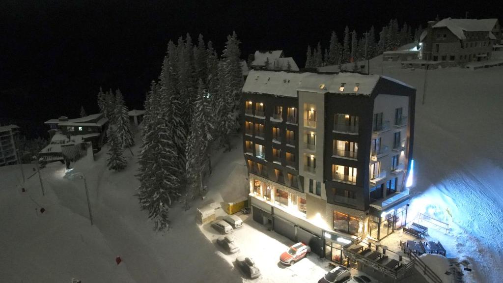 a building with lights in the snow at night at Apartman Drvorez Jahorina in Jahorina