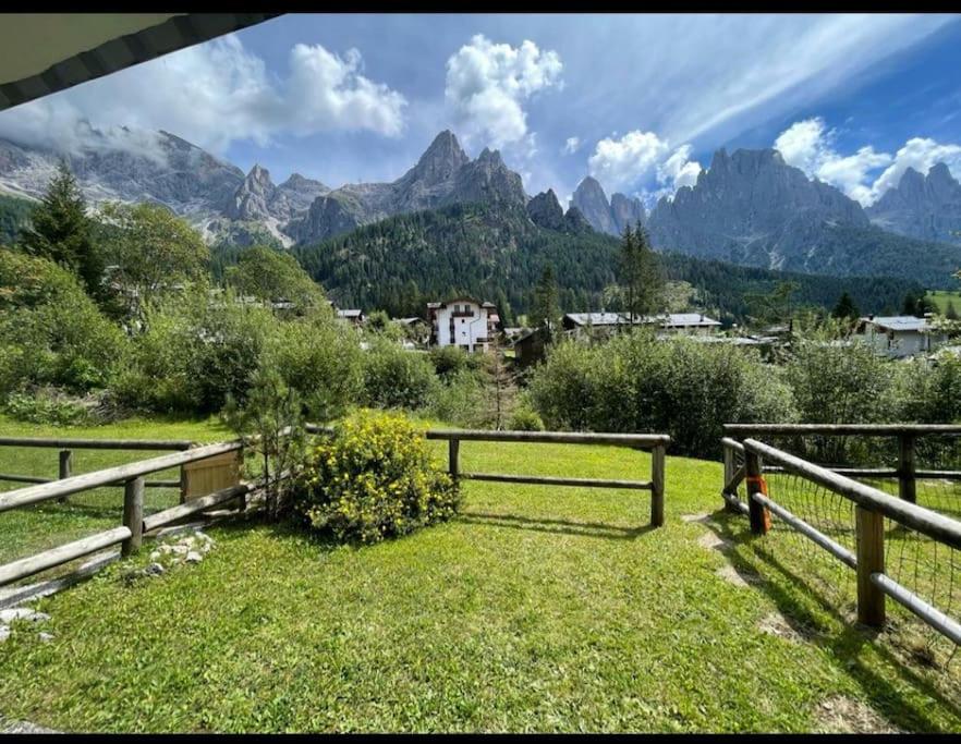 a field with a fence and mountains in the background at Stella Alpina San Martino di Castrozza vista Pale in San Martino di Castrozza