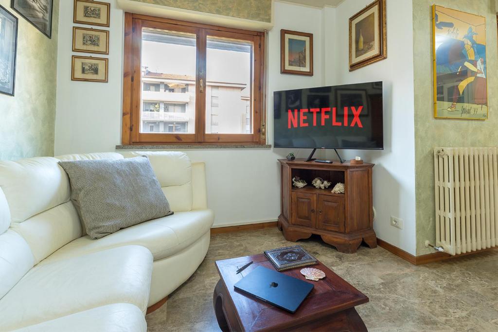 een woonkamer met een witte bank en een televisie bij Shell Apartment - Spazioso Attico Con WiFi Gratuito e Posto Auto in Perugia