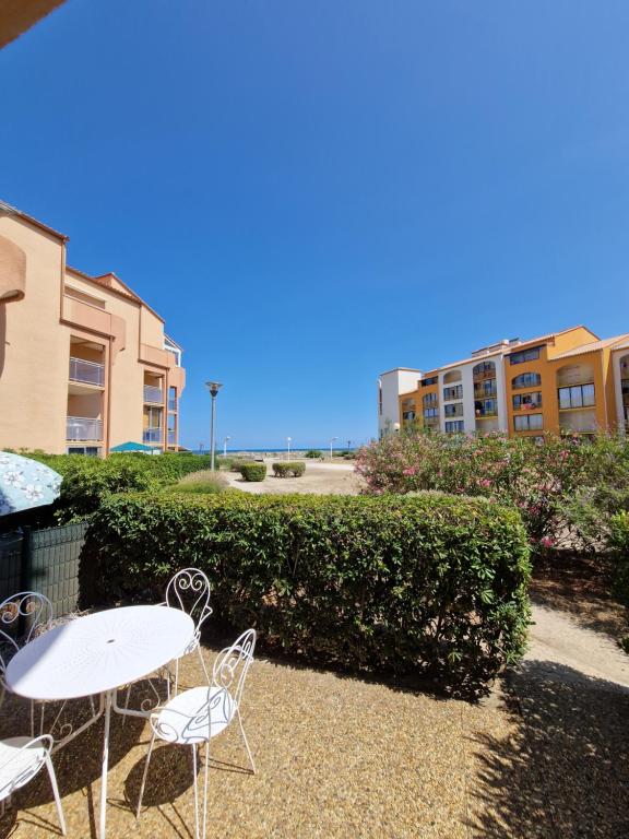 un patio avec des tables et des chaises en face d'un bâtiment dans l'établissement T2 rez de jardin direct plage, au Barcarès