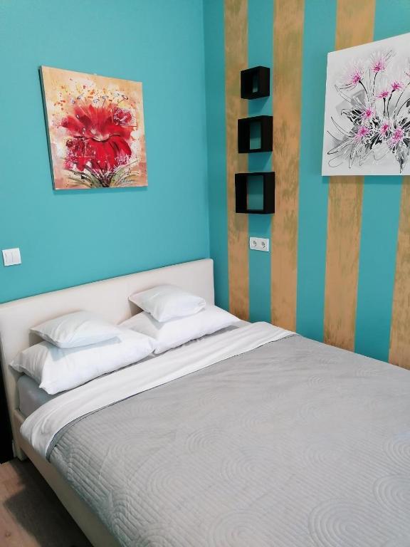 1 dormitorio con 1 cama con una pintura en la pared en Queency Apartament cu gradina și parcare gratuita en Cluj-Napoca