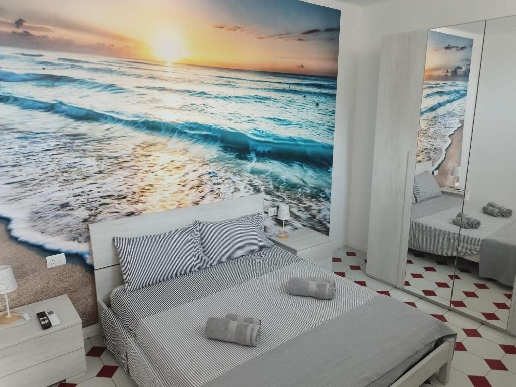 um quarto com uma cama e uma cena de praia em Nuovo bilocale a 150 mt dal mare em Porto Torres