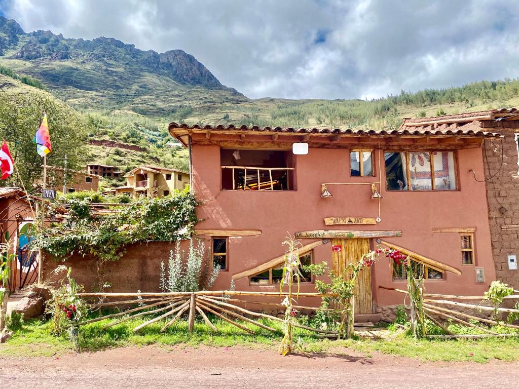 une maison avec une clôture en face d'une montagne dans l'établissement Wallpari Sonqo Hospedaje Medicina temazcal, à Pisac
