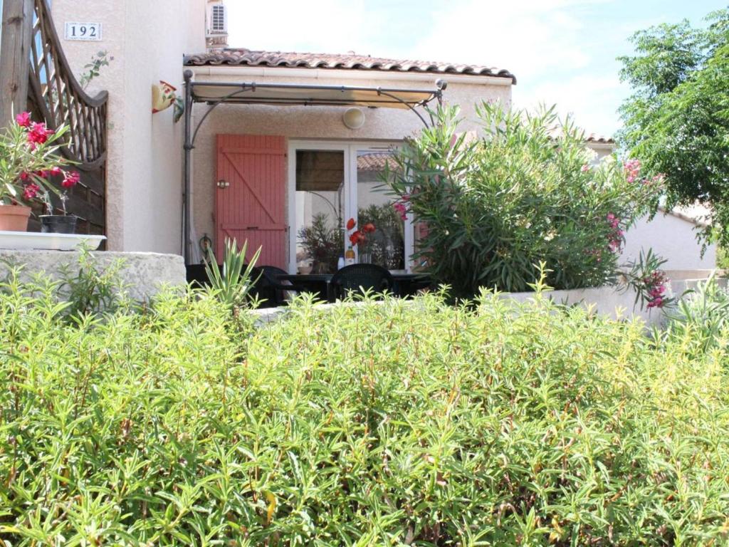 une maison avec une porte rouge et quelques buissons dans l'établissement Maison de Vacances avec Piscine et Terrasse, 800m de la Plage - 6 Couchages, Saint Pierre la Mer - FR-1-229D-82, à Fleury