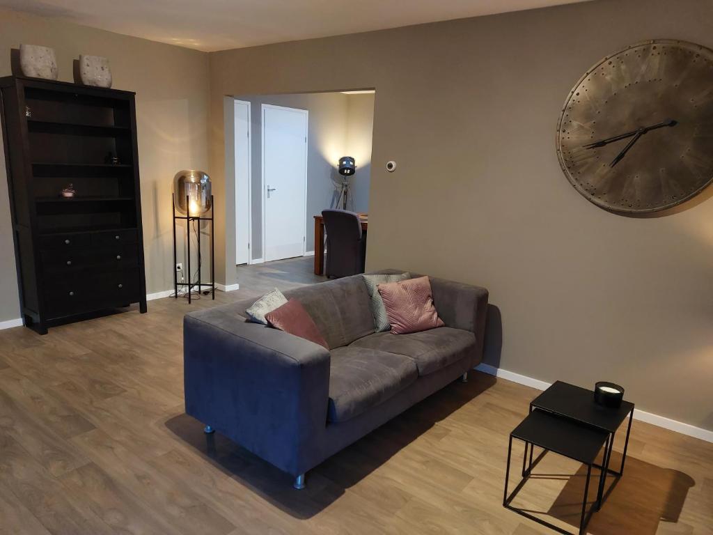 a living room with a couch and a large clock on the wall at B&Bie Ons appartement in Bad-Nieuweschans