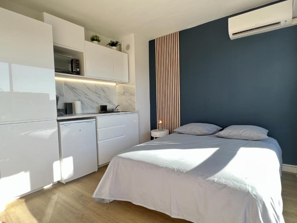 - une chambre avec un lit blanc et un mur bleu dans l'établissement Studio Beaux Arts - *Proche centre *Clim *Balcon, à Montpellier