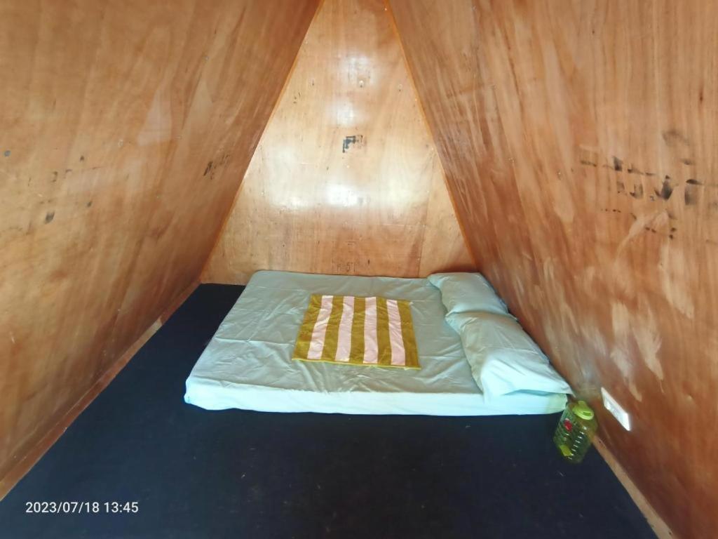Habitación pequeña con cama en una pared de madera. en Croods Farm Stay - Kodaikanal en Kodaikānāl