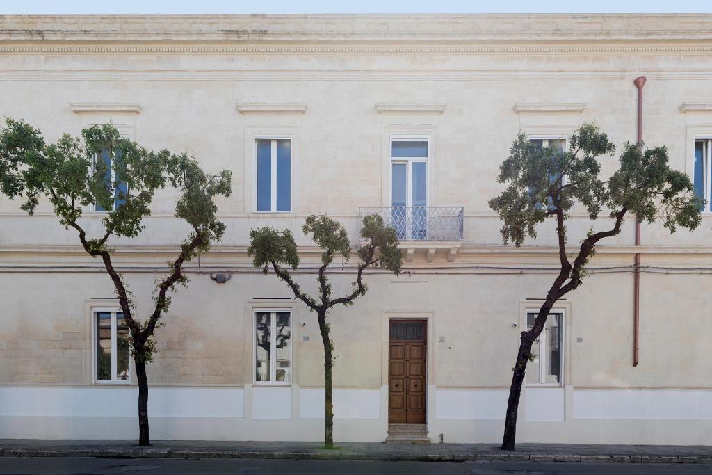 un edificio blanco con árboles delante de él en Palazzo Ricciardi Residence, en Lecce