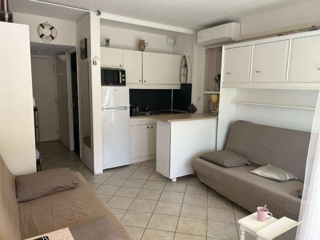 un salon avec un canapé et une cuisine dans l'établissement Studio climatisé 4 couchages avec piscine et parking, accès direct plage - Port Camargue - FR-1-250-162, au Grau-du-Roi