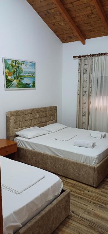 two beds in a room with white walls at Hotel Lepenica in Vlorë