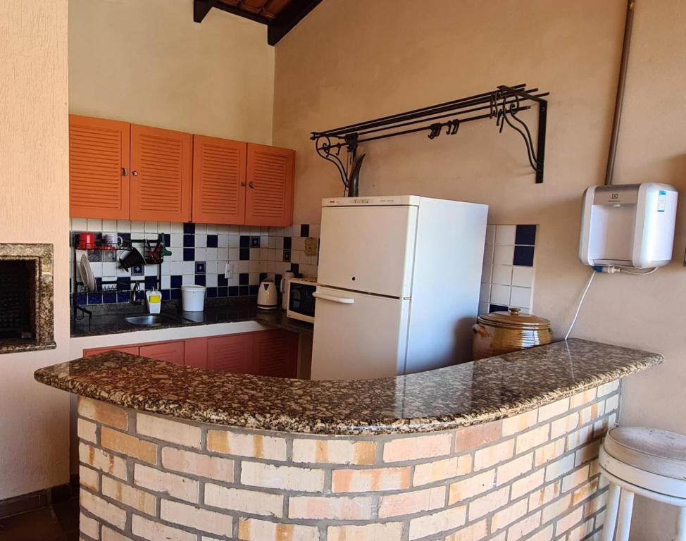 a kitchen with a brick counter with a refrigerator at Hostel Oktoberfest casa laranja in Blumenau