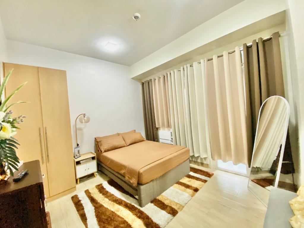 a bedroom with a bed and a large window at Homey-feel Studio Unit @ Lafayette Park Square Condominium in Iloilo City