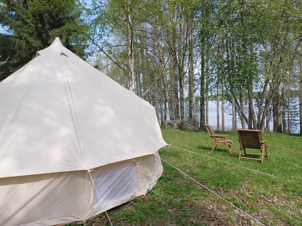 a tent and a chair in a field at Glamping tent Pielinen 