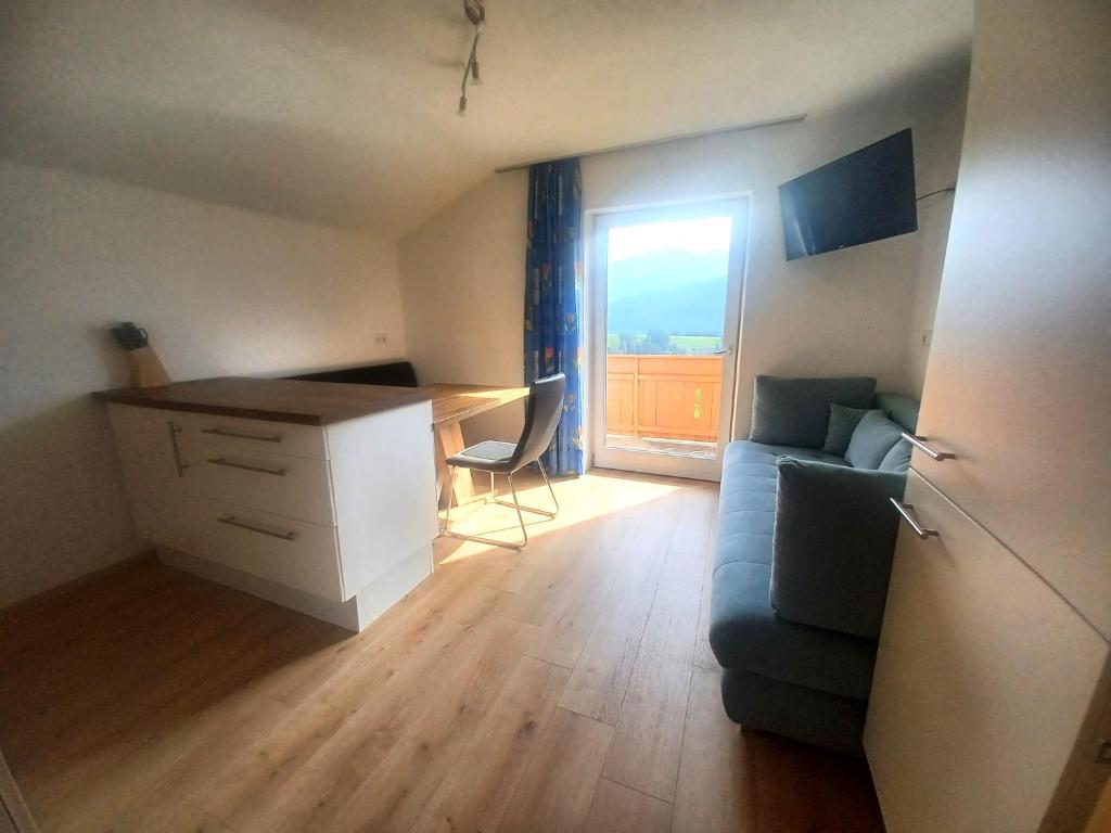 uma sala de estar com um sofá, uma secretária e uma janela em Ferienwohnung Wipptalblick em Navis