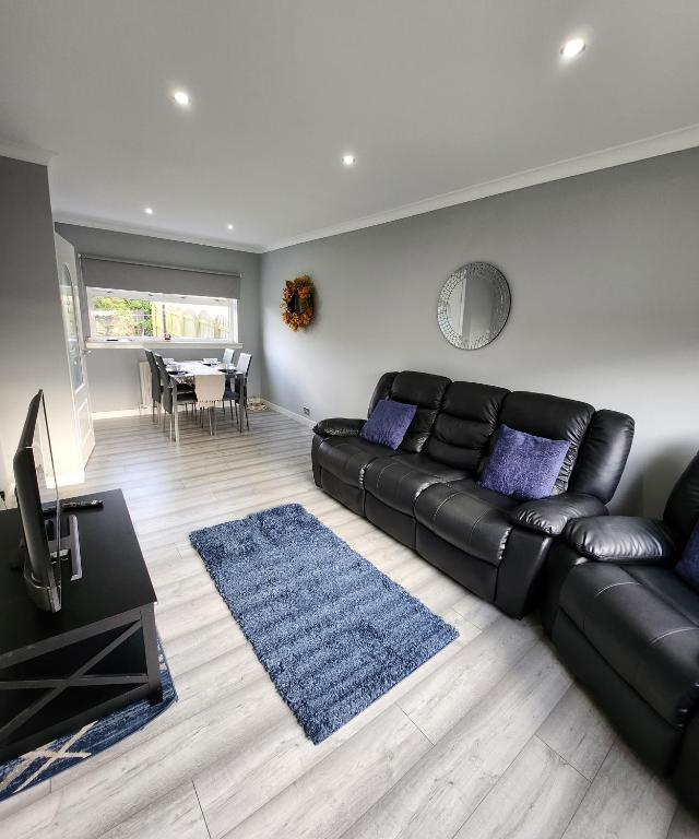 a living room with a black leather couch and a blue rug at Stunning 3 bedroom FMHomes & Apartments in Uddingston