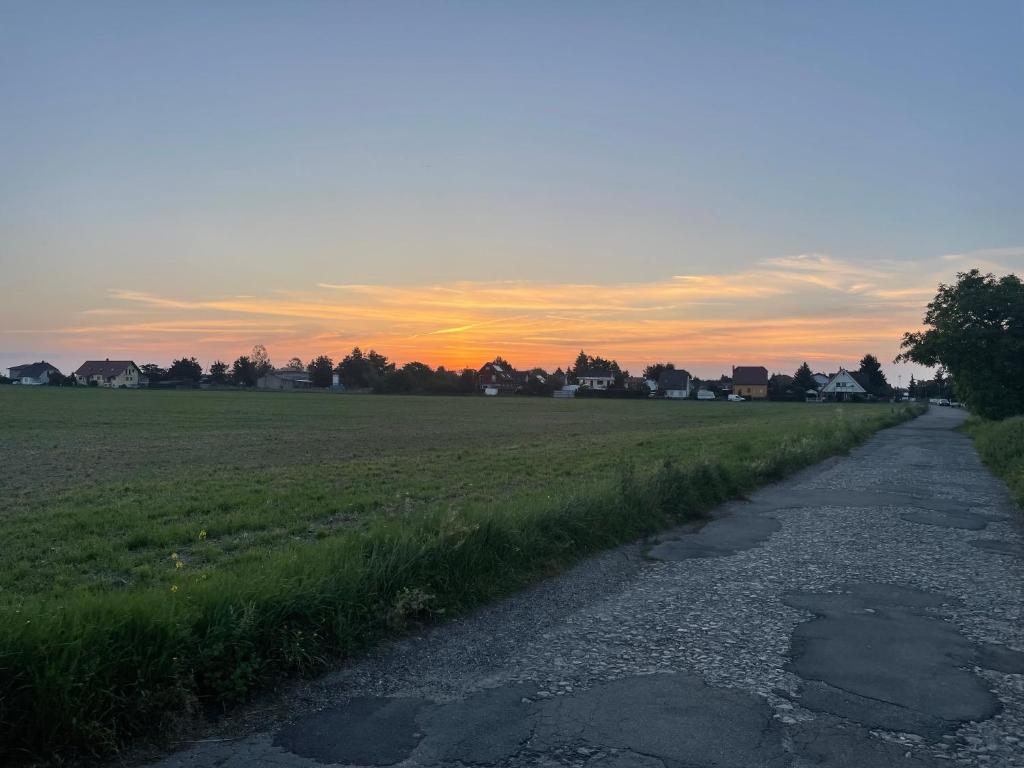un camino en un campo con la puesta de sol en el fondo en Grüne Oase, en Leipzig