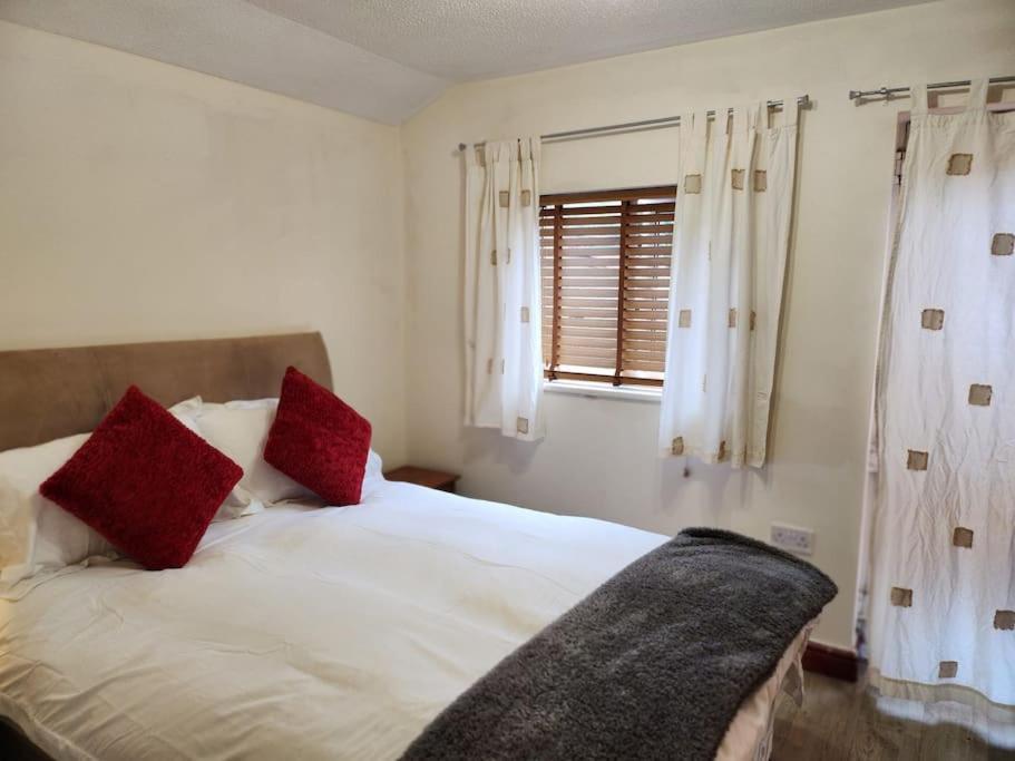 a bedroom with a bed with red pillows and a window at * Cotswolds Get-Away Annex * in Cleeve Prior