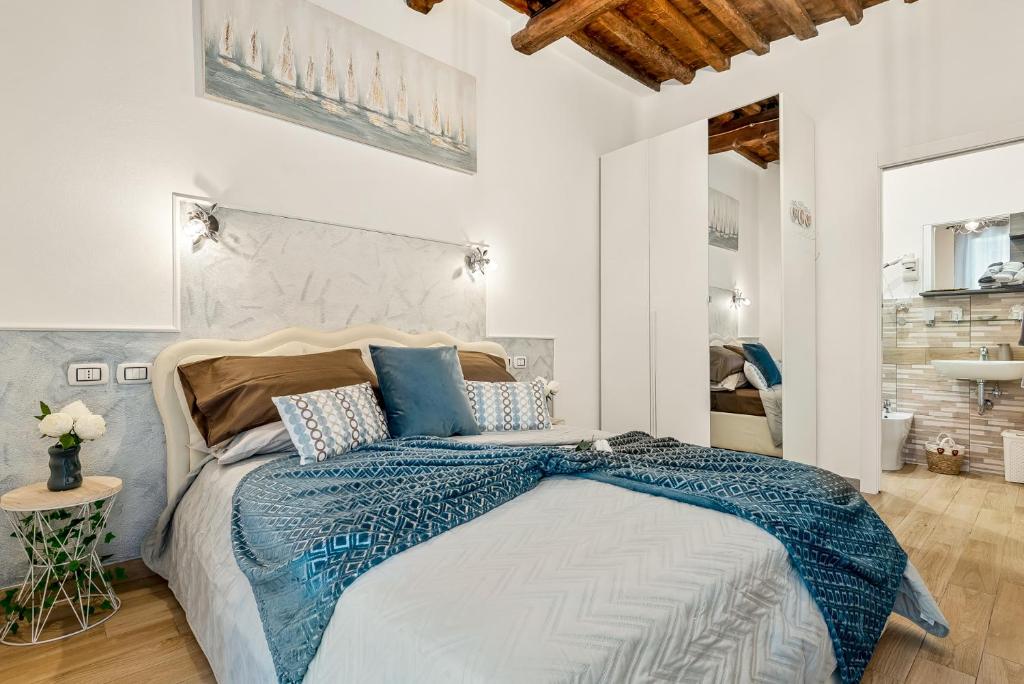 a white bedroom with a large bed with blue comforter at Alby Express Rooms in La Spezia