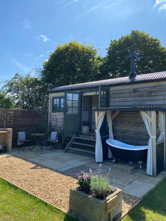 a tiny house with a bath tub in the yard at The Rabbit Warren Shepherd Hut in Ketton