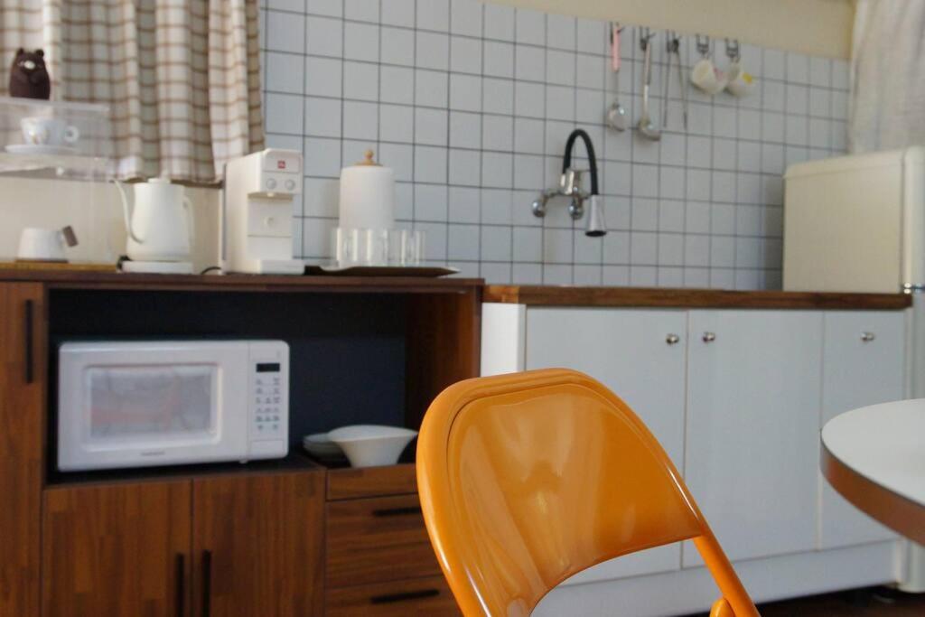 kuchnia z pomarańczowym krzesłem i kuchenką mikrofalową w obiekcie Zibro w mieście Gunsan
