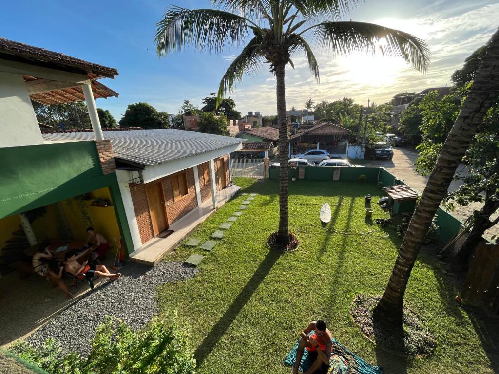 a group of people sitting in a yard with palm trees at Pousada Luz da Vila Itaúnas in Itaúnas