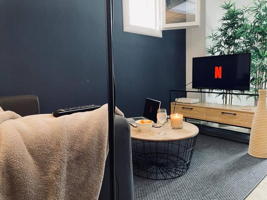 un salon avec une table et une télévision dans l'établissement Le Fauriel - Parking gratuit - Centre ville, à Saint-Étienne