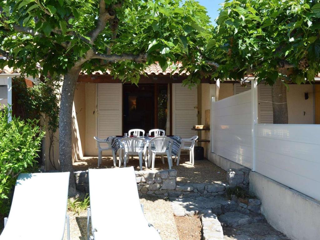 d'une terrasse avec des chaises et une table sous un arbre. dans l'établissement Charmant studio mezzanine pour 4 pers. à 800m de la plage avec piscine et tennis - FR-1-229D-85, à Fleury