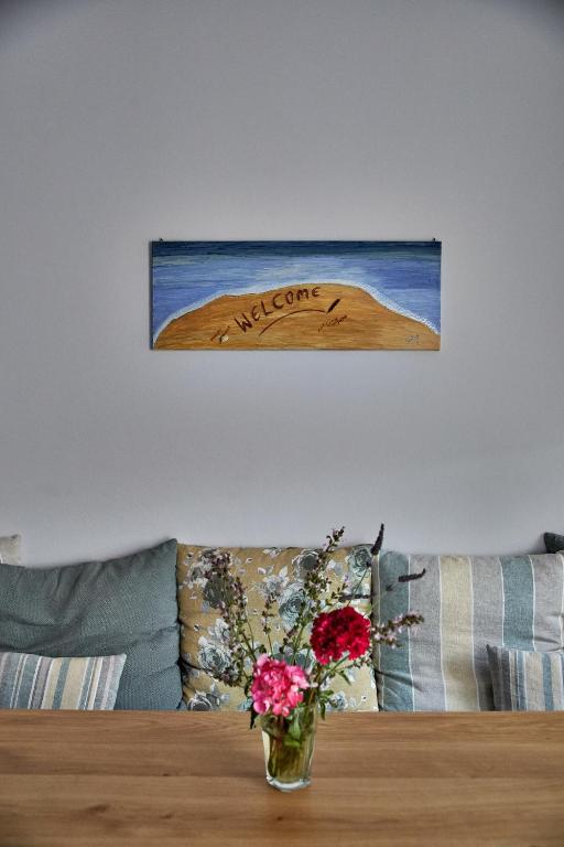 a vase of flowers on a table with a painting on the wall at Irene Studios in Agios Petros
