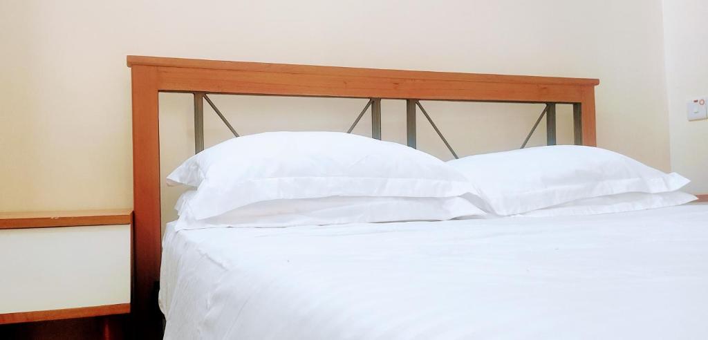 łóżko z białą pościelą i poduszkami w obiekcie Elrad Residence Villa by Monalisa w mieście Morogoro